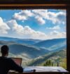 A person working remotely on a laptop while enjoying a scenic mountain view, representing Workation destinations in India.