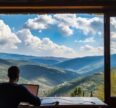 A person working remotely on a laptop while enjoying a scenic mountain view, representing Workation destinations in India.