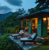 Cozy Coorg homestay surrounded by lush greenery, with mountain views, outdoor lounge chairs, and warm interior lighting.