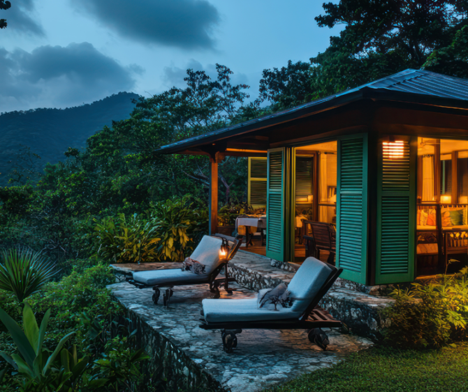 Cozy Coorg homestay surrounded by lush greenery, with mountain views, outdoor lounge chairs, and warm interior lighting.