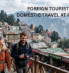 Crowded hill-station street with domestic and foreign tourists, mountain views, and colonial buildings. Text overlay reads, “Foreign Tourists Down, Domestic Travel at Record High.”
