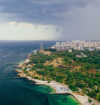 Aerial view of a scenic coastal city with the sea, green landscape, beaches, and modern buildings, highlighting Goa real estate investment opportunities.