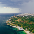 Aerial view of a scenic coastal city with the sea, green landscape, beaches, and modern buildings, highlighting Goa real estate investment opportunities.