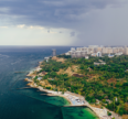 Aerial view of a scenic coastal city with the sea, green landscape, beaches, and modern buildings, highlighting Goa real estate investment opportunities.
