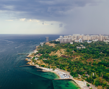 Aerial view of a scenic coastal city with the sea, green landscape, beaches, and modern buildings, highlighting Goa real estate investment opportunities.
