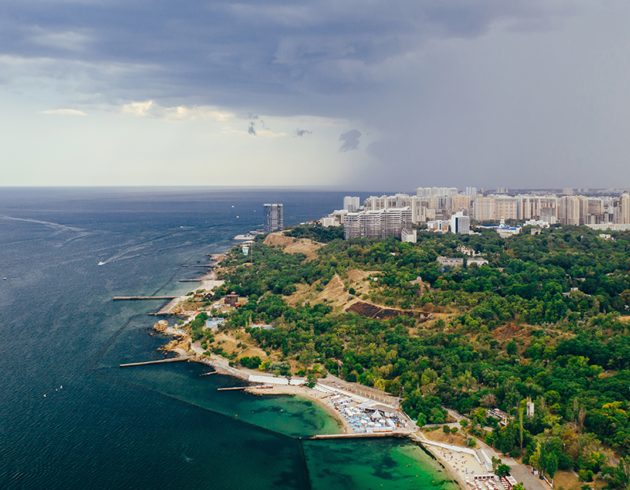 Aerial view of a scenic coastal city with the sea, green landscape, beaches, and modern buildings, highlighting Goa real estate investment opportunities.