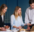 Professionals discussing real estate investment as part of long-term wealth planning with property models and financial documents