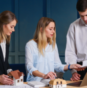 Professionals discussing real estate investment as part of long-term wealth planning with property models and financial documents
