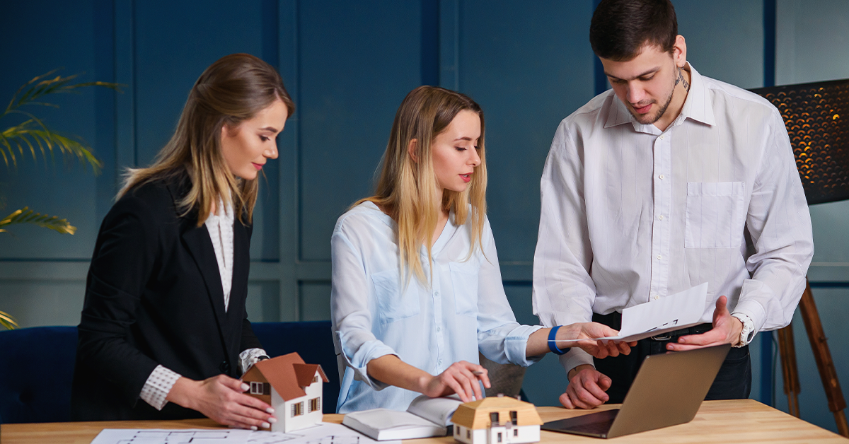 Professionals discussing real estate investment as part of long-term wealth planning with property models and financial documents