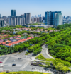 Noida cityscape with modern commercial towers, residential buildings, green spaces, and a major road intersection