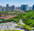Noida cityscape with modern commercial towers, residential buildings, green spaces, and a major road intersection