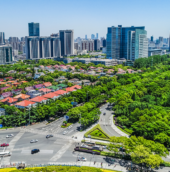 Noida cityscape with modern commercial towers, residential buildings, green spaces, and a major road intersection