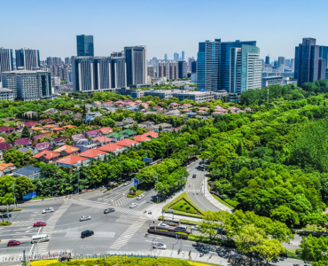 Noida cityscape with modern commercial towers, residential buildings, green spaces, and a major road intersection