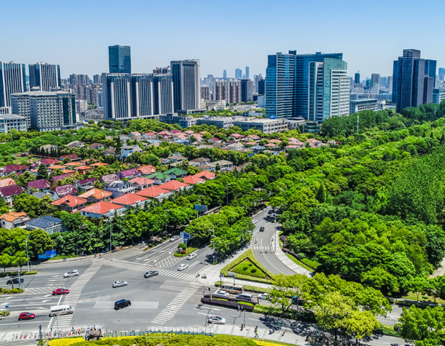 Noida cityscape with modern commercial towers, residential buildings, green spaces, and a major road intersection