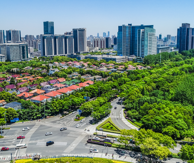 Noida cityscape with modern commercial towers, residential buildings, green spaces, and a major road intersection