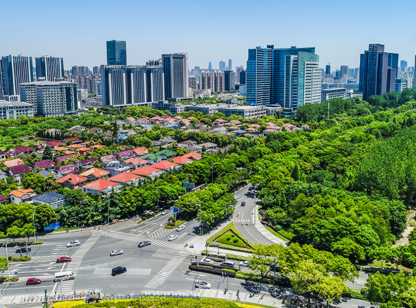 Noida cityscape with modern commercial towers, residential buildings, green spaces, and a major road intersection