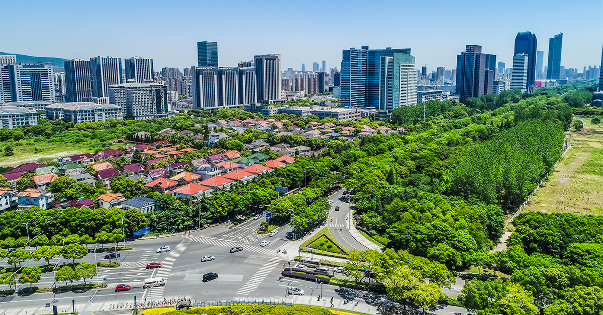 Noida cityscape with modern commercial towers, residential buildings, green spaces, and a major road intersection