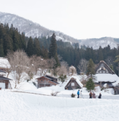 Snow-covered traditional thatched-roof houses in a mountain village with pine forest and snowy peaks in the background If you do want to keep it as a generic "snowy hill village" mood image despite the mismatch, a softer, less location-specific option: