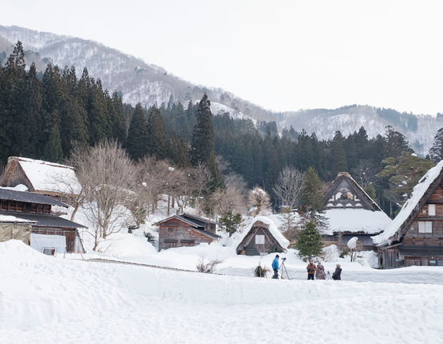 Snow-covered traditional thatched-roof houses in a mountain village with pine forest and snowy peaks in the background If you do want to keep it as a generic "snowy hill village" mood image despite the mismatch, a softer, less location-specific option: