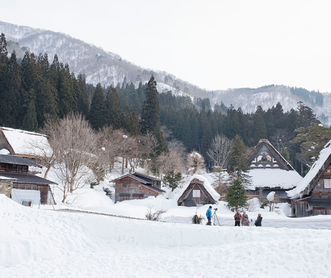 Snow-covered traditional thatched-roof houses in a mountain village with pine forest and snowy peaks in the background If you do want to keep it as a generic "snowy hill village" mood image despite the mismatch, a softer, less location-specific option:
