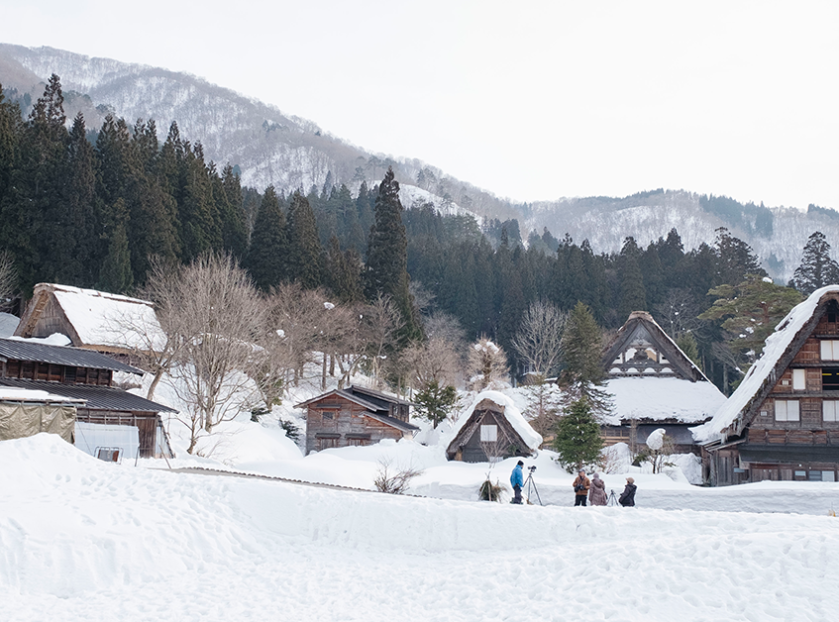 Snow-covered traditional thatched-roof houses in a mountain village with pine forest and snowy peaks in the background If you do want to keep it as a generic "snowy hill village" mood image despite the mismatch, a softer, less location-specific option: