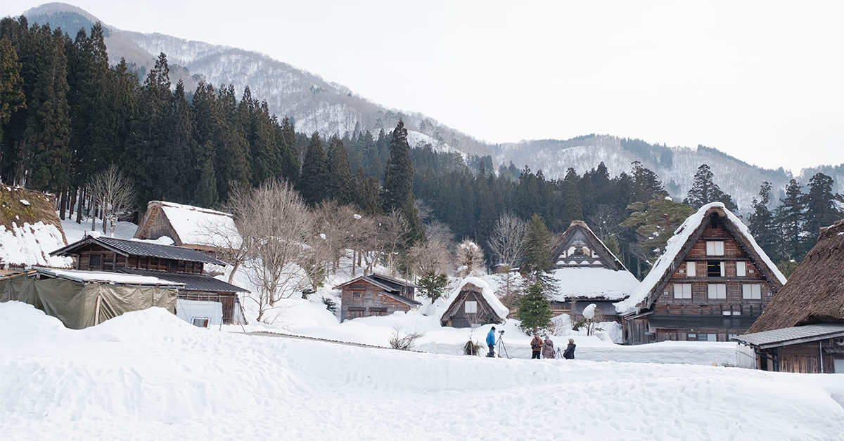 Snow-covered traditional thatched-roof houses in a mountain village with pine forest and snowy peaks in the background If you do want to keep it as a generic "snowy hill village" mood image despite the mismatch, a softer, less location-specific option: