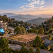 Kasauli apartments surrounded by lush green hills, featuring modern architecture and contrasting arrows illustrating real estate price trends at sunset.