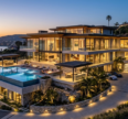 Luxury real estates featuring a modern coastal villa with an infinity pool, elegant architecture, and stunning ocean views at sunset.
